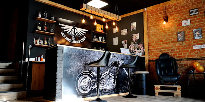 Wnętrze Wild Angel Barber Studio w Kłodzku — bar z logo, mural chopera, ceglana ściana i skórzane fotele